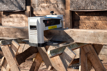 Tool is smoothing a wooden plank on a worktable outside under clear blue skiesの写真素材