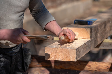 A skilled artisan carves wood with a hand tool in a bright workshop on a warm day.の写真素材