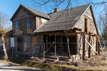 Construction workers restore a historic wooden house in a peaceful countryside setting.の写真素材