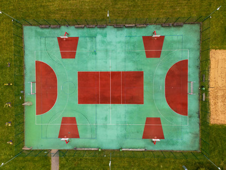 Aerial view of a vibrant sports court surrounded by green grass and trees during daytime.の写真素材