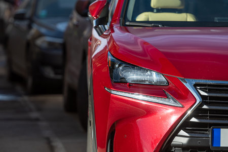 Close-up view of a shiny red car highlighting the front grille and headlightsの写真素材