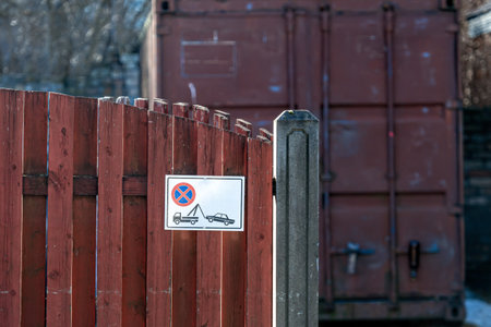 A parking regulations sign is visible on a wooden fence adjacent to storage containers.