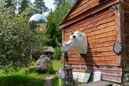 Rustic building display includes cow head sculpture and disco ball surrounded by nature.の写真素材