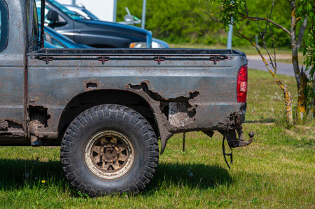 Weathered pickup truck displays rust and wear, parked beside other vehicles in daylight.の写真素材