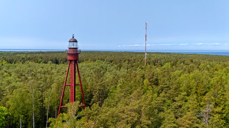 Historic lighthouse stands tall among the dense forests of Ruhnu Island with sea views.の写真素材