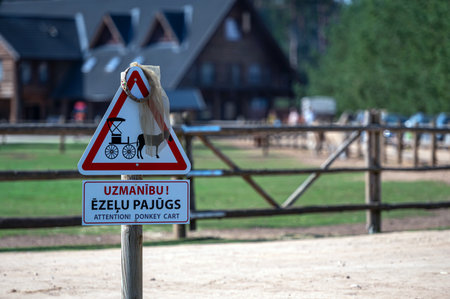 A warning sign alerts visitors about donkeys present near a stable in a farm area.の写真素材