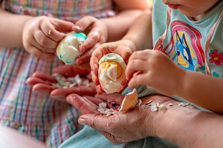 Two children enjoy decorating eggs while sitting together on a sunny spring day.の写真素材