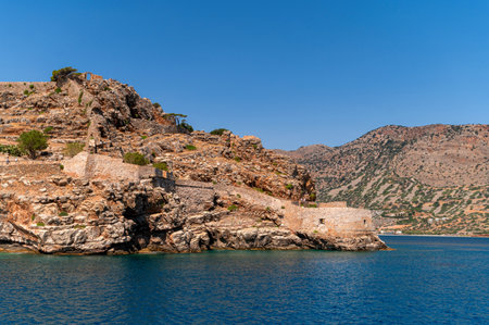 Visitors admire Spinalonga Island's stunning coast and ancient ruins in bright sunlight.の写真素材