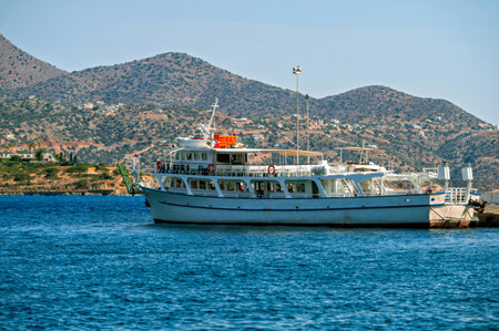 A large boat is anchored at the harbor of Agios Nikolaos, Crete under clear skies.の写真素材