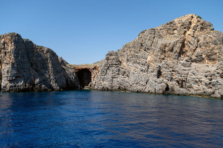 Visitors admire the rugged cliffs of Crete while enjoying the sparkling sea on a sunny day.の写真素材