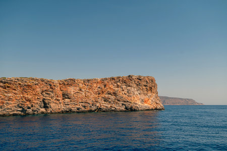 Turquoise waters gently lap against rugged cliffs of Crete, highlighting serene coastal beauty.の写真素材