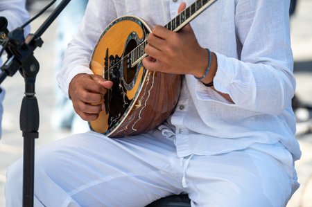 A performer skillfully strums a bouzouki while dressed in light clothing in Crete, Greece.の写真素材