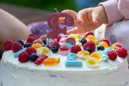 Brightly decorated cake with assorted fruits and a number candle during a joyful gathering