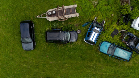 Several abandoned cars and a truck sit among tall grass in a sunny outdoor setting.の写真素材