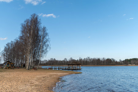 Relaxing lakeside scene in Valdemarpils, Latvia featuring a sandy shore and wooden dock.の写真素材