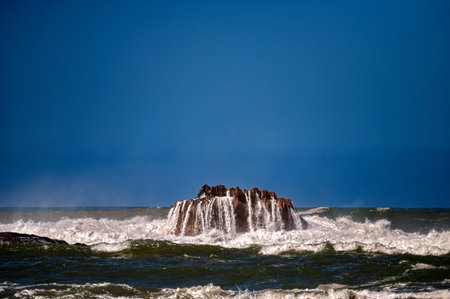 Waves crashing against rocky outcrop in Essaouira, Morocco during a clear dayの写真素材
