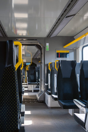 Seats line the train interior with space in the middle and light coming through windows