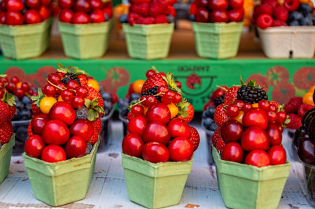 People visit a market in Prague to buy fresh fruits displayed in green containers.
