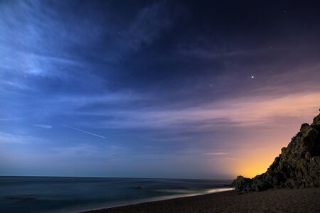 Night sky with moonlight clouds over the coastlineの写真素材