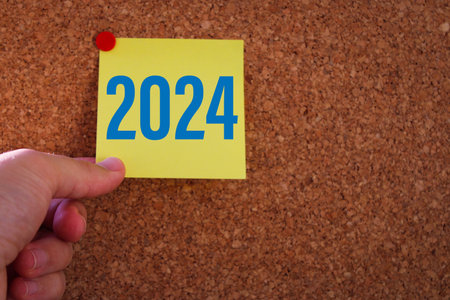 A man's hand pulling out a sticky note. year change from 2023 to 2024. 2024 year concept idea.