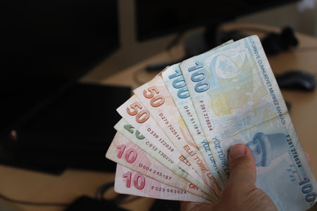 man counting Turkish banknotes with his hand.Calculator in the background. For tax and hike news. raise, tax, minimum wage.の写真素材