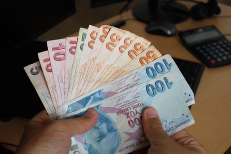 man counting Turkish banknotes with his hand.Calculator in the background. For tax and hike news....