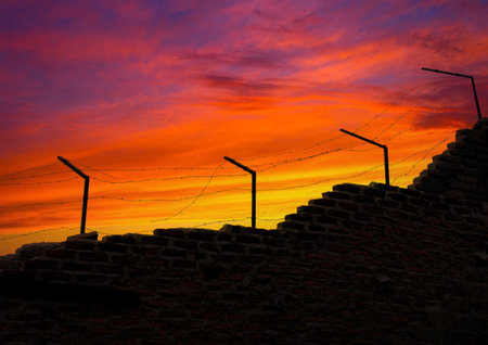 Prison wall and electric fences at sunset. freedom themed photo.