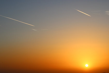 airplane and its trail in the sky. clouds and different color tones in the sky at sunset. Amazing and incredible sunset.の写真素材