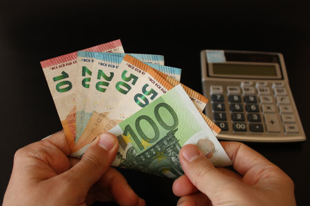 man counting euro money with his hand. euro banknotes. The paper currency of europan union .Calculator in the background.の写真素材