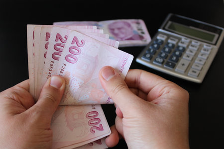 Turkish 200 lira banknotes.man counting Turkish money with his hand.Calculator in the background....