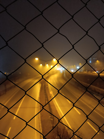 Highway behind metal fences. Foggy Night Highwayの写真素材