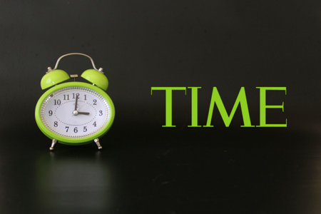 Green alarm clock with time text. Clock and time themed photoの写真素材