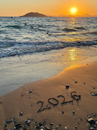 2026 new year concept. 2026 Written in Sand on a Beach with Golden Sunset Reflection.