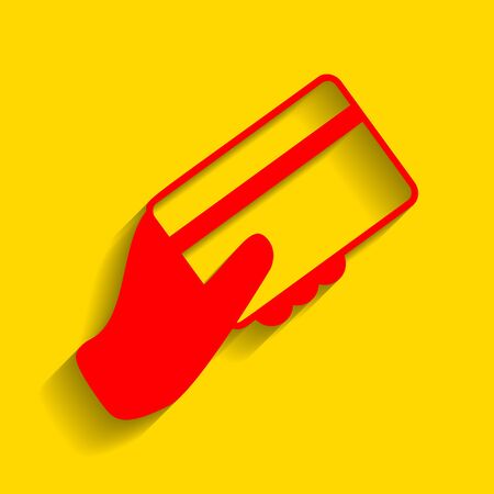 Hand holding a credit card. Vector. Red icon with soft shadow on golden background.のイラスト素材