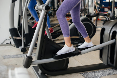 Two young beautiful girls exercise in the gym wearing masks during the pandemic. Social distancing in public places.の写真素材