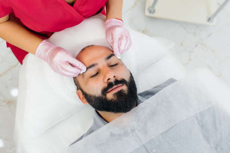 A young man is undergoing a cosmetic facial peeling procedure. Cosmetology and rejuvenationの写真素材