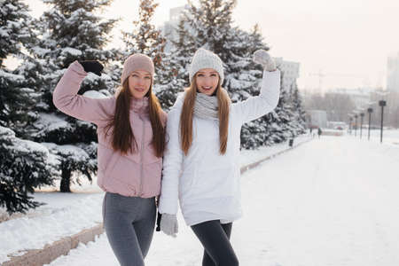 Two young athletic girls walking and playing sports on a sunny winter day. A healthy way of life.の写真素材