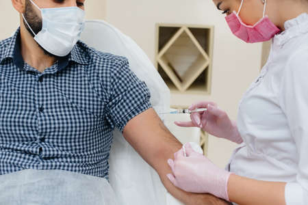 Vaccination of a man against flu and coronavirus infection during a worldwide pandemic. The formation of the immune system and antibodies.の写真素材