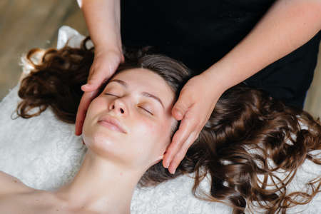 A young pretty girl is enjoying a professional head massage at the Spa. Body care. Beauty salon