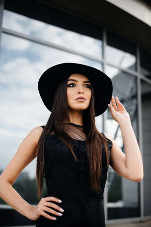 Stylish young and sexy girl posing in front of a business center in black. Fashion and styleの写真素材