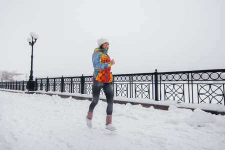 A beautiful young girl is Jogging on a frosty and snowy day. Sports, healthy lifestyle