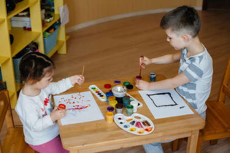 A boy and a girl play together and paint. Recreation and entertainment. Stay at home