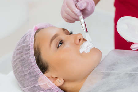 Moisturizing the lips during a cosmetic procedure for a young girl. Cosmetologyの写真素材