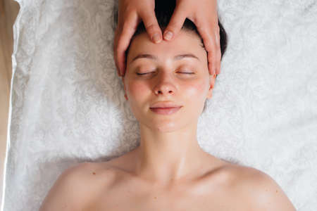 A young pretty girl is enjoying a professional head massage at the Spa. Body care. Beauty salonの写真素材