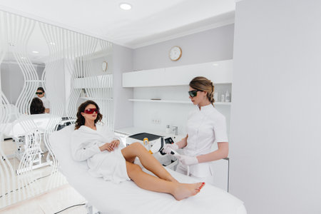 A beautiful young girl will undergo laser hair removal with modern equipment in a Spa salon. Beauty salon. Body careの写真素材