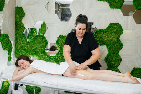 A young pretty girl is enjoying a professional massage using honey at the Spa. Body care. Beauty salonの写真素材