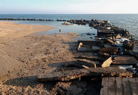 on a sunny autumn day, under the blue sky you can see plates, stones, piles on the shore of the Sea of Azovの写真素材