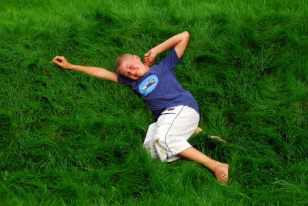 young boy is resting on the grass in the gardenの写真素材