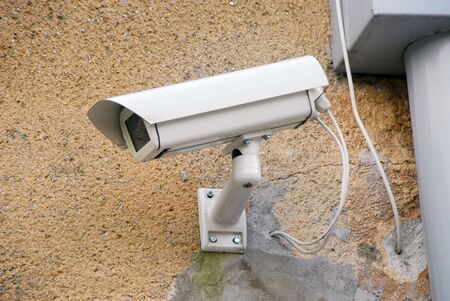 Closeup of a white generic security camera on the wall.