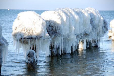 Frozen breakwater in the Baltic sea in sunny weatherの写真素材
